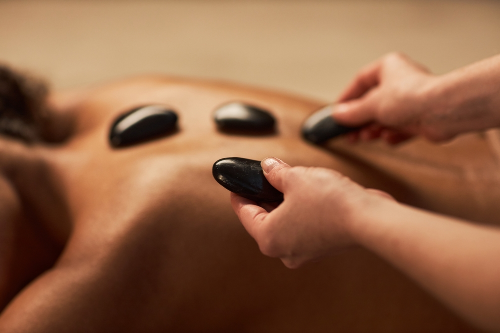 A therapist placing hot stones on a customer’s back