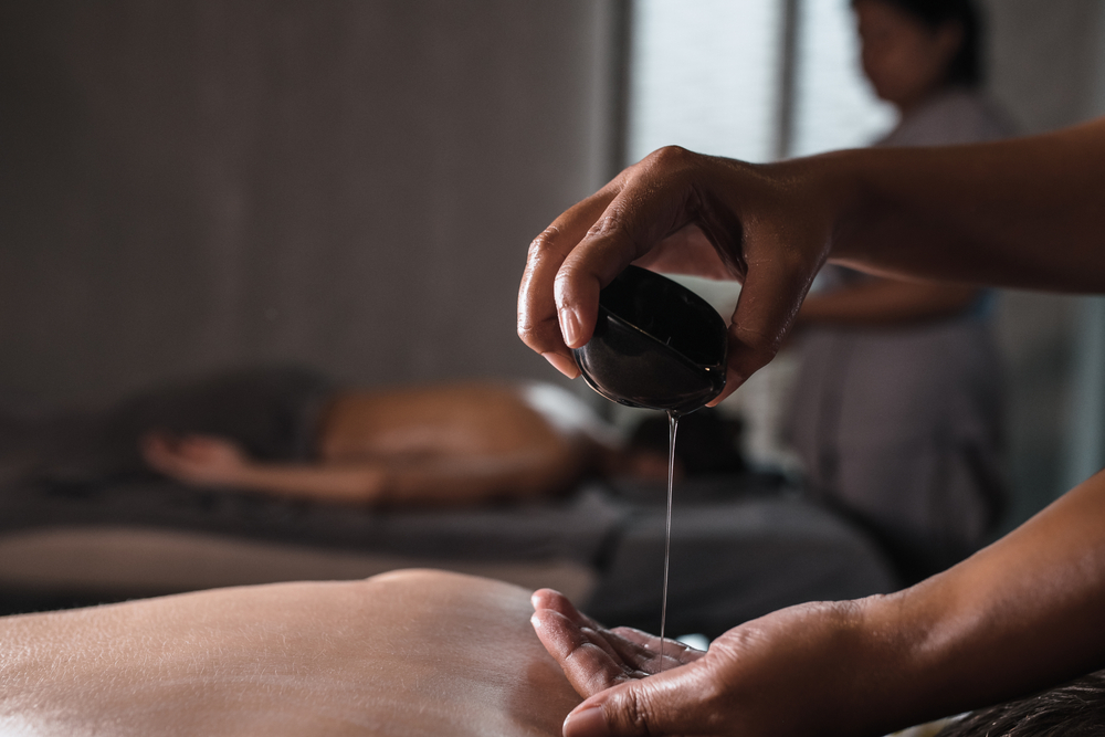 A therapist pouring oil on her hand during a massage