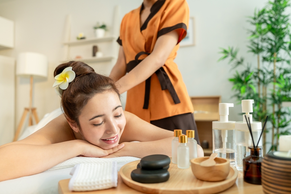 young woman receives an aromatherapy massage, with bottles of essential in view