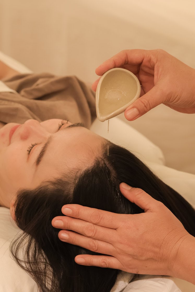Lavender oil being poured over a woman receiving a head massage at Makkha Spa, Chiangmai, renowned for relaxing spa treatments.