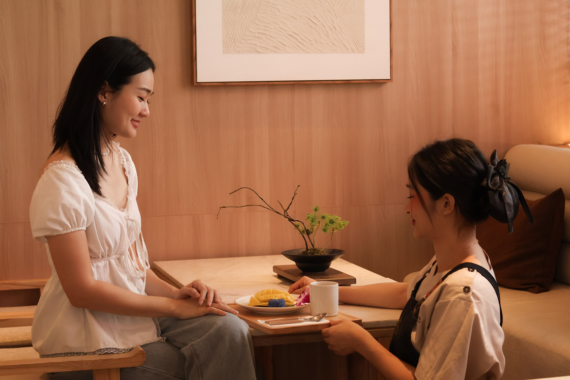 Woman enjoying mango sticky rice and herbal tea after facial massage at spa