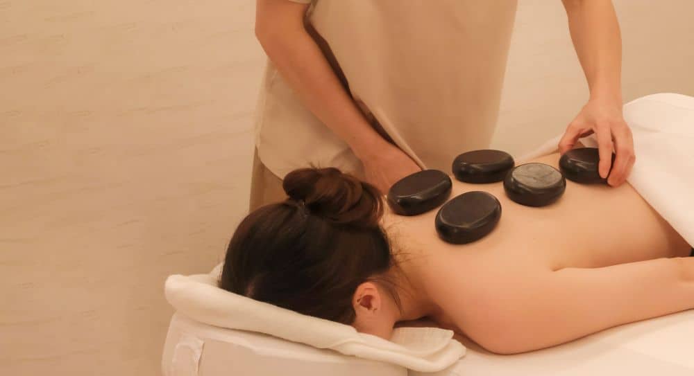 Warm basalt stones placed on a guest's back during a hot stone massage at a boutique Thai spa.