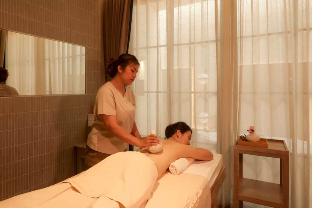 A woman enjoying a Thai herbal ball massage at a spa during a Bangkok spa trip