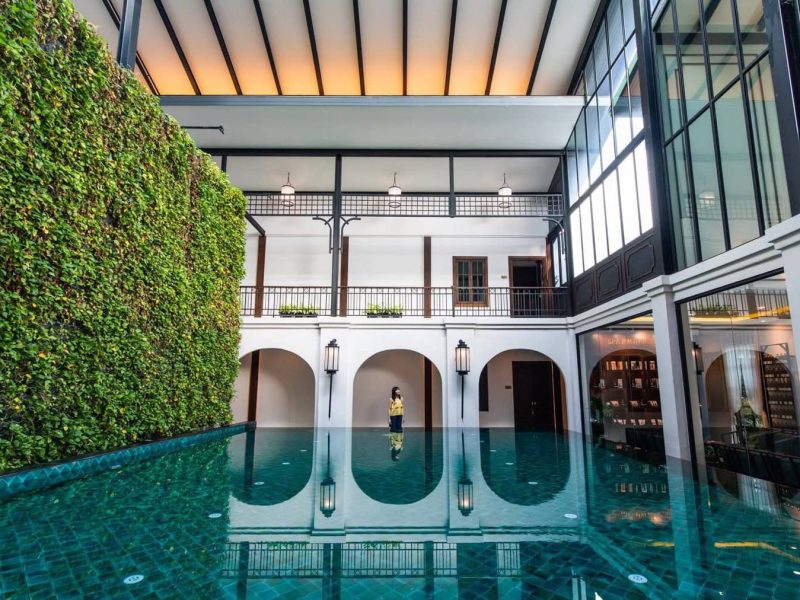 Luxurious indoor swimming pool at Makkha Spa, Chiang Mai, with lush greenery wall, natural lighting, elegant architecture, perfect for relaxation and wellness.
